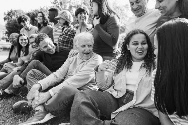 Group of multigenerational people having fun together - Multiracial friends of different ages smiling outdoor - Main focus on african curvy girl face - Black and white editing